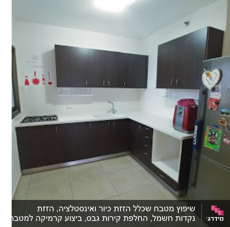 מטבח עם ארונות כהים, מקרר ותמונות על הקיר